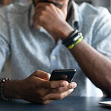 An African American male holds a mobile phone