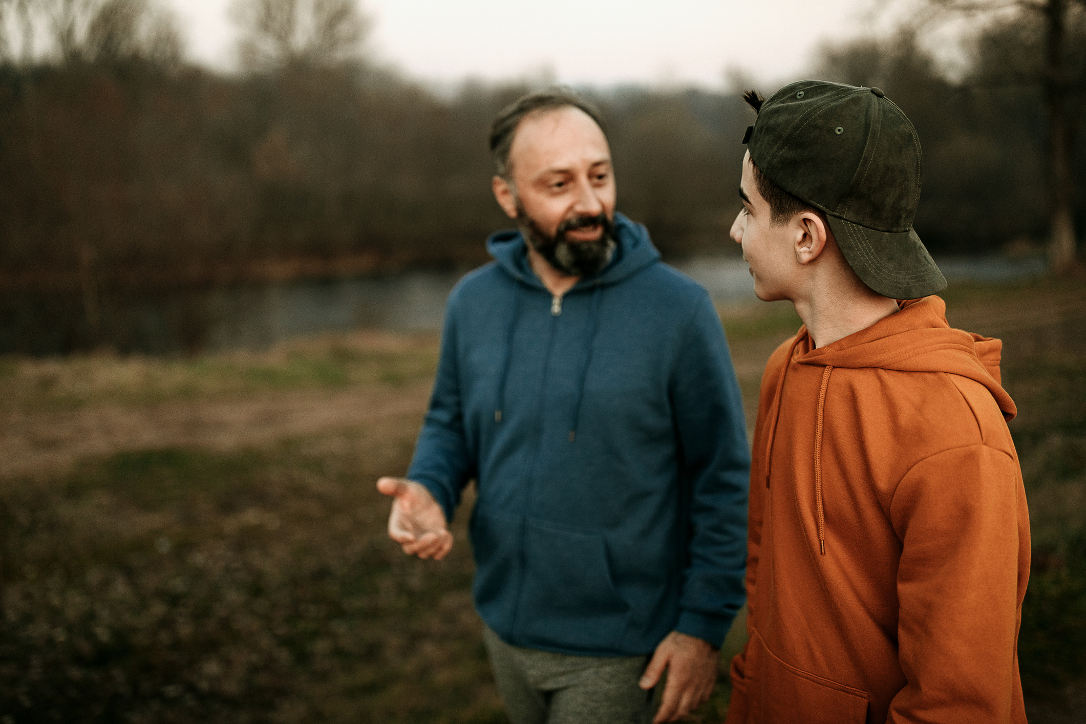 A father and son talking as they walk in a park.