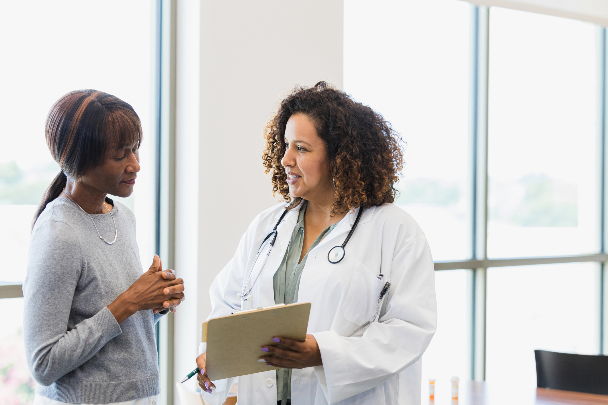 A doctor and her patient look at information on a clipboard.