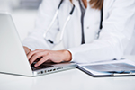 A doctor types on a laptop computer, representing clinical decision support systems to prevent cardiovascular disease.