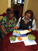 Two women at a table review educational materials, represent community health workers engaging to prevent cardiovascular disease.