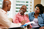 Man sits on couch and talks with midlle aged man and woman, represents interventions engaging community health workers to prevent diabetes