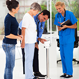 A doctor and nurse record a patient's weight