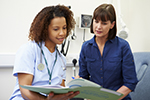 A nurse reviews a medical file with a female patient.