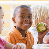 A group of kindergartners eat a healthy lunch.