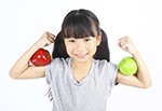 A young girl holding two apples.