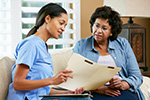 A Community Health Worker reviews a medical chart with a patient.