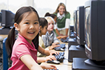 A young girl sits in front of a school computer.