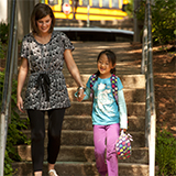 A teacher walks a student to the school building.