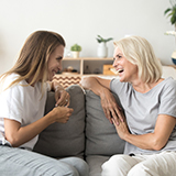 Two women sitting on a couch while talking.