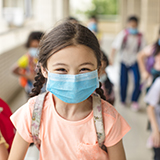 Elementary school children walk through a school hallway.