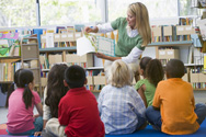 A teacher turns the pages of a picture book for a group of children