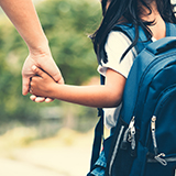 A parent and child walk hand in hand.