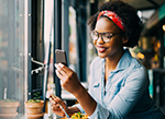 A woman eating lunch while looking at a smart phone.